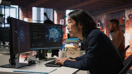 Software engineer in small business workspace using computer to oversee artificial intelligence...
