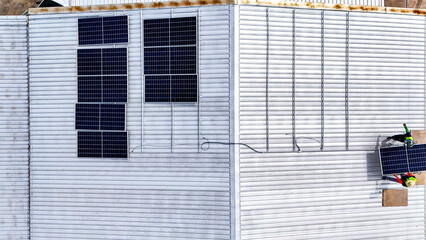 A sustainable energy project featuring solar panels on a roof surrounded by tropical trees,...