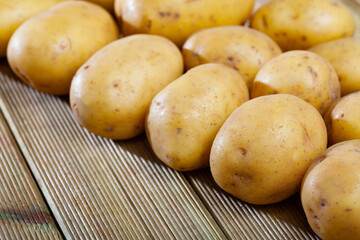 Image of raw fresh young potatoes at wooden table in home kitchen, nobody..