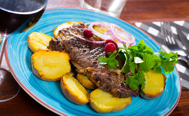 Juicy beefsteak served with baked potato and herbs on plate