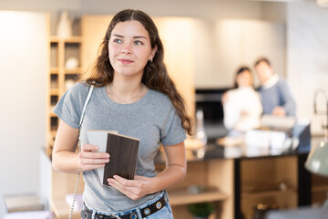 Fototapeta premium Female buyer with samples of material chooses kitchen set in a furniture store