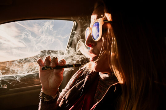 Profile of a woman smoking a vape in her car
