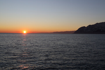 silhouette of mountain peak hill edge on Black sea sunshine background Sarpi Sarpi national Border between Georgia Turkey. sun rays beam sunburst sunray blue sky Sea landscape over mountain in sunset