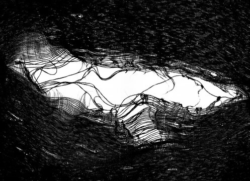 teared rag spread isolated on white background , can use like a backdrop or pattern texture. hole in the tissue. black fabric with torn stitch, hole and loose threads Torn fabric with frayed edges