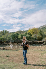 Dad with a little girl on his shoulders stands near a paddock with a horse in the park