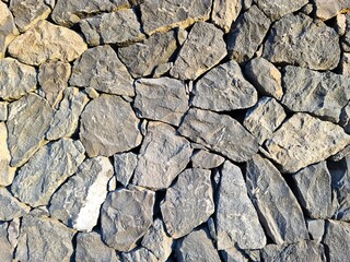 Rough stone wall forming a textured background under sunlight