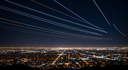 Obraz premium Dynamic motion meets urban beauty—a stunning capture of an aircraft’s light trails intertwined with the city’s sparkling night,landscape, aerodrome, night scene, city skyline