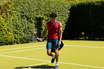 Obraz premium Young man playing tennis on court, smiling and enjoying sunny day outdoors, copy space