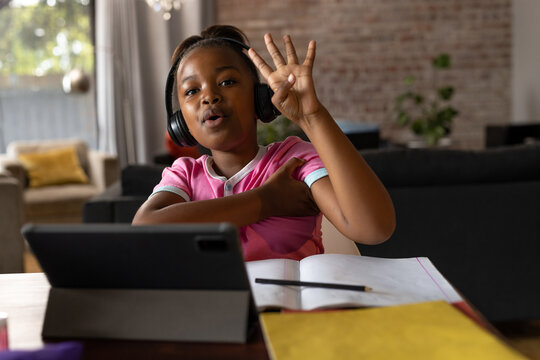 In school, child learning online at home, wearing headphones, raising hand, copy space