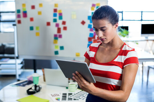 Focused woman using tablet in modern office with colorful sticky notes, copy space