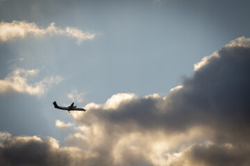 A turboprop aircraft flying through clouds at dusk, ready for landing, captured with dramatic sky and atmospheric lighting.