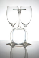 A sleek lineup of three elegant, empty wine glasses with long stems, reflecting on a glossy surface against a soft gray background, perfect for dining or event themes.