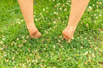 Person walking barefoot on grass with visible heel details and natural surroundings.