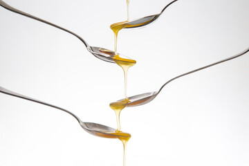 Fresh floral honey drips from a spoon into a spoon on a white background. Organic vitamin food.