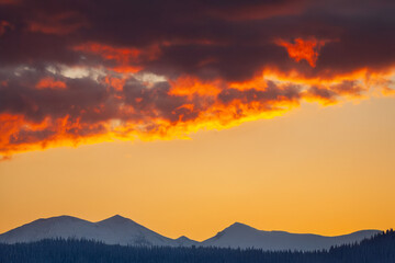 Dramatic cloudy sky with golden sunlight breaking through at sunset. A mix of dark storm clouds and soft illuminated areas creates a moody and atmospheric scene.