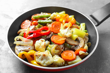 Different vegetables and mushrooms in frying pan on grey table, closeup