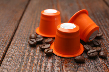Coffee capsules and beans on wooden table, closeup. Space for text