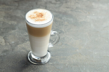 Tasty latte macchiato in glass cup on grey table, closeup. Space for text