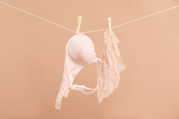 Beautiful bra and panties hanging on rope against dark beige background