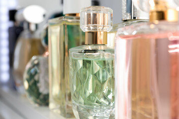 Different aromatic perfumes in bottles on shelf, closeup
