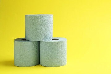 Light blue toilet paper rolls on yellow background, space for text
