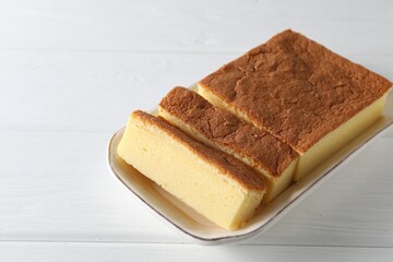 Tasty Japanese Castella sponge cake on white wooden table, closeup. Space for text
