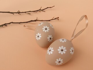 Decorated Easter eggs and dried branches on salmon background.