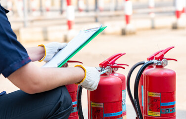 A safety officer inspector checks gauge indicates of  the fire extinguishers.
