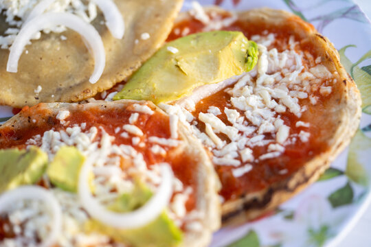 acercamiento a picadas fritas con salsa, queso, cebolla y aguacate