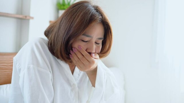 asian woman feeling sick in the morning with nausea and vomiting, possibly due to pregnancy, low blood sugar, stomach flu, indigestion, or other health issues
