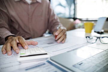 close-up shot, hand of asian man using calculator to calculate expenses and income after starting...