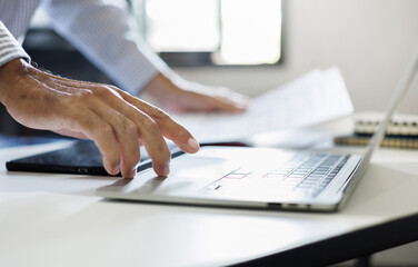 close up shot, man hand using laptop working and review document on desk at home. work from home concept