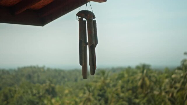A wind chime hangs on the roof of a shabby wooden house in a village