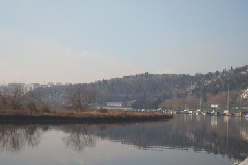 Tranquil waters reflect the green landscape near a distant town