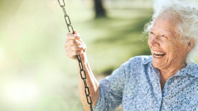 Cheerful senior woman on a swing at a playground