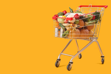 Shopping cart full of food on yellow background