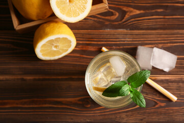 Glass of fresh lemonade with mint and ice cubes on wooden background
