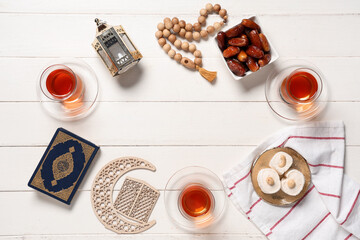 Frame made from glasses of tasty Turkish tea, Koran, fanoos and sweets on white wooden background....