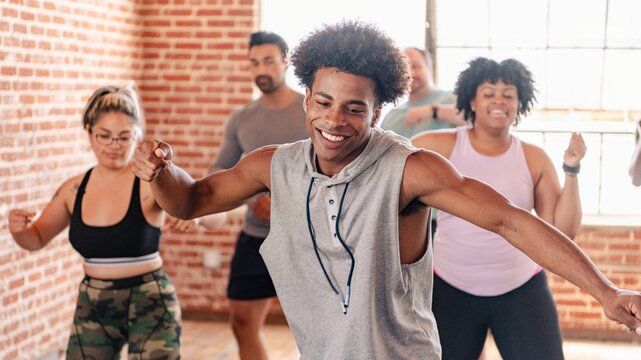 Group dance class with diverse participants enjoying exercise. Smiling individuals in a bright studio, moving energetically in a fun dance workout. Diverse people exercising in fitness class.