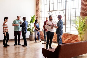 Diverse group of people in casual modern office, discuss ideas. Diverse men and women team in office, casual social meeting. Group of diverse team in modern office meeting, socialize and share ideas