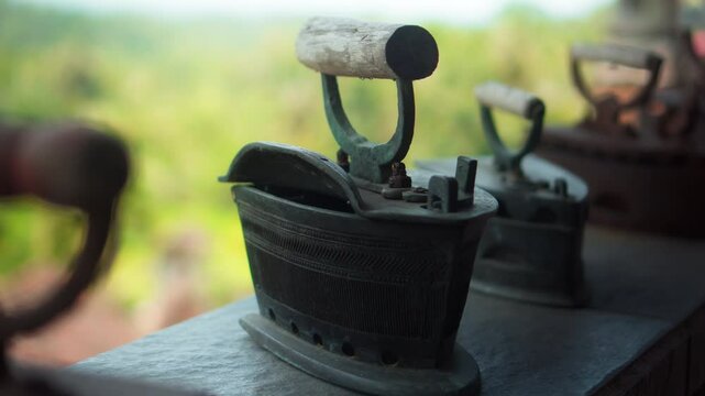 Antique rusty charcoal iron for ironing clothes with wooden handle stands on a shelf
