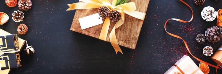 Festive gifts with ribbons and pinecones on a dark background. Holiday gifts, pinecones, and...