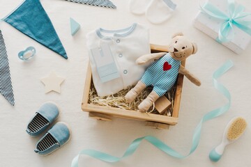 Baby gift set with blue accents, featuring a teddy bear, baby clothes, and shoes. Perfect baby...