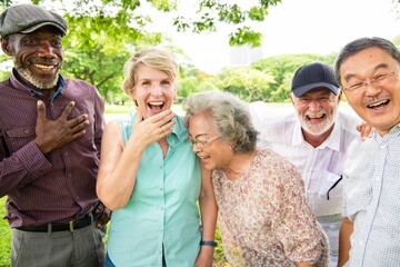 Group of diverse elderly friends laughing outdoors. Elderly joy, diverse smiles, and outdoor fun....