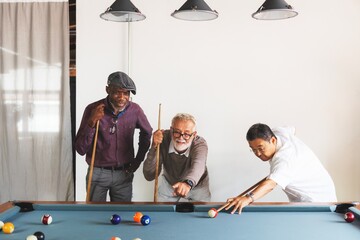 Three diverse elderly men playing pool. Diverse old men enjoying a game. Diverse group of elderly...
