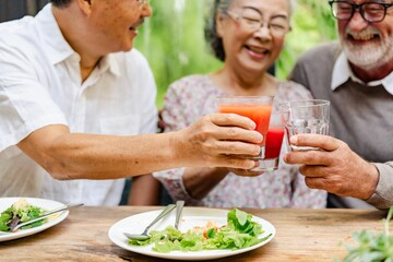Diverse seniors clinking glasses, celebrate healthy lifestyle. Diverse senior hands toast with healthy drinks. Social gathering, healthy food and drinks. Healthy seniors celebrate at social gathering