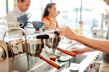 Close up photo of a barista's hand making coffee with a coffee machine in cafe coffee shop. Barista's hands operating coffee machine, preparing coffee in cafe. Barista focused on coffee preparation
