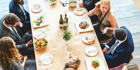 A diverse group of people, including men and women, enjoying a gourmet meal at a long table. The elegant dining setting features delicious dishes, wine, and lively conversation.