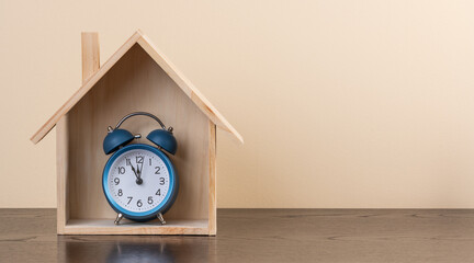 Symbolic wooden house and alarm clock
