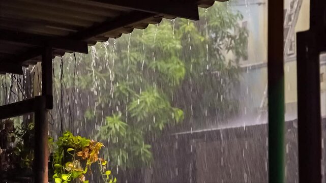 Heavy rain pouring from a roof's edge, blurring the green foliage in the background, creating a tranquil and serene atmosphere